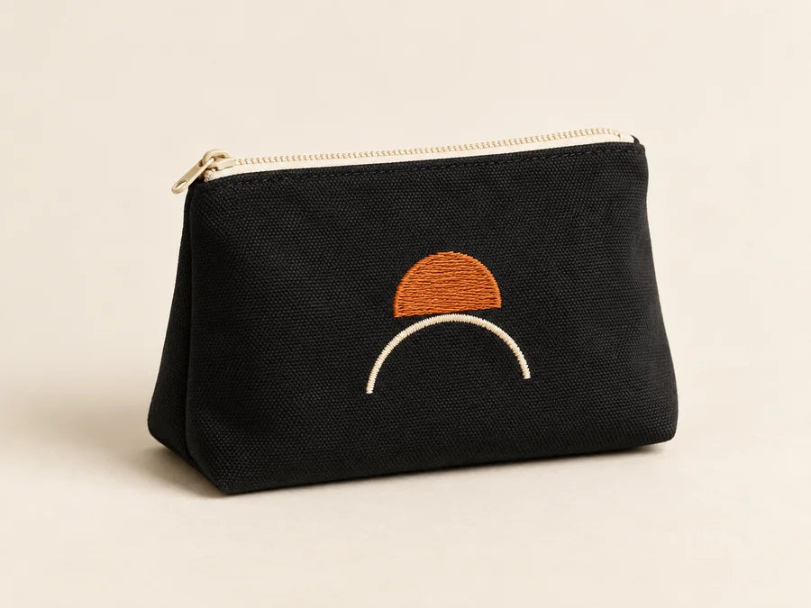 Illustrative black pouch with orange embroidery, shown as a design concept.